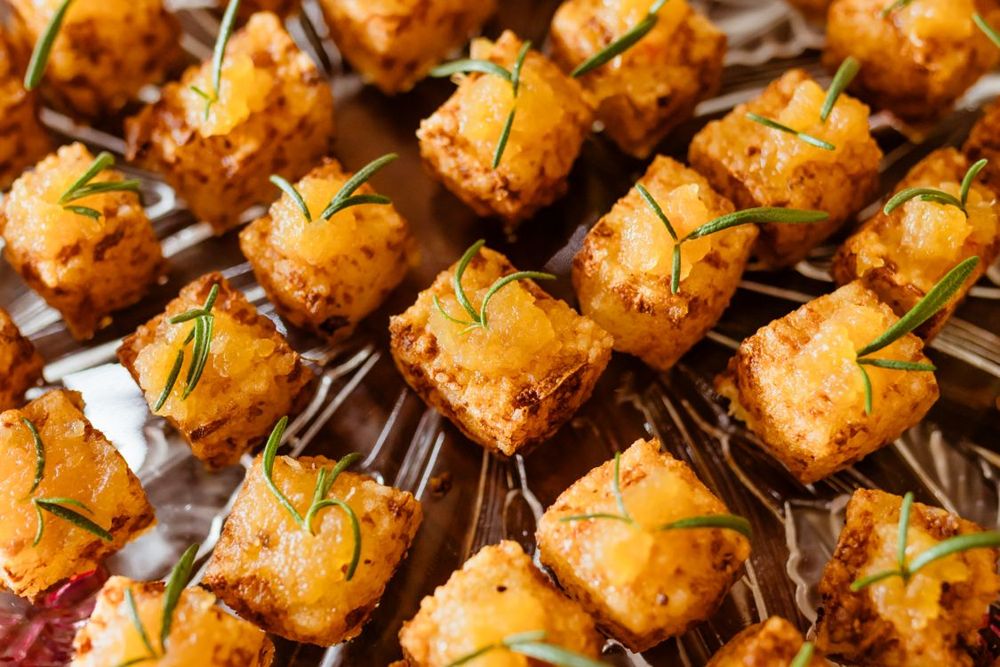 Golden crusted tofu cubes arranged on a platter with rosemary sprigs.