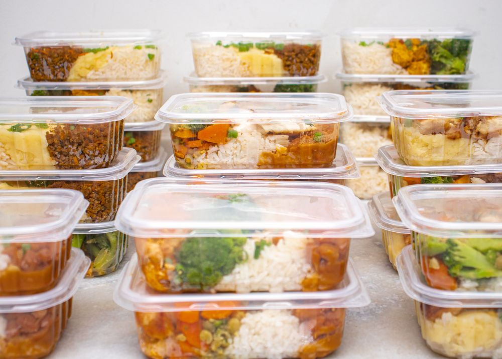 A stack of closed meal prep containers filled with rice and vegetables.